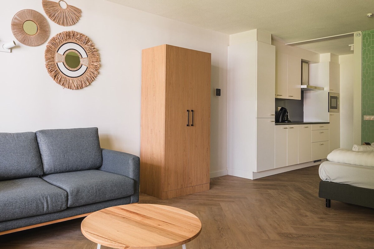 A modern living room with a grey sofa, a wooden cabinet, and a round wooden table.