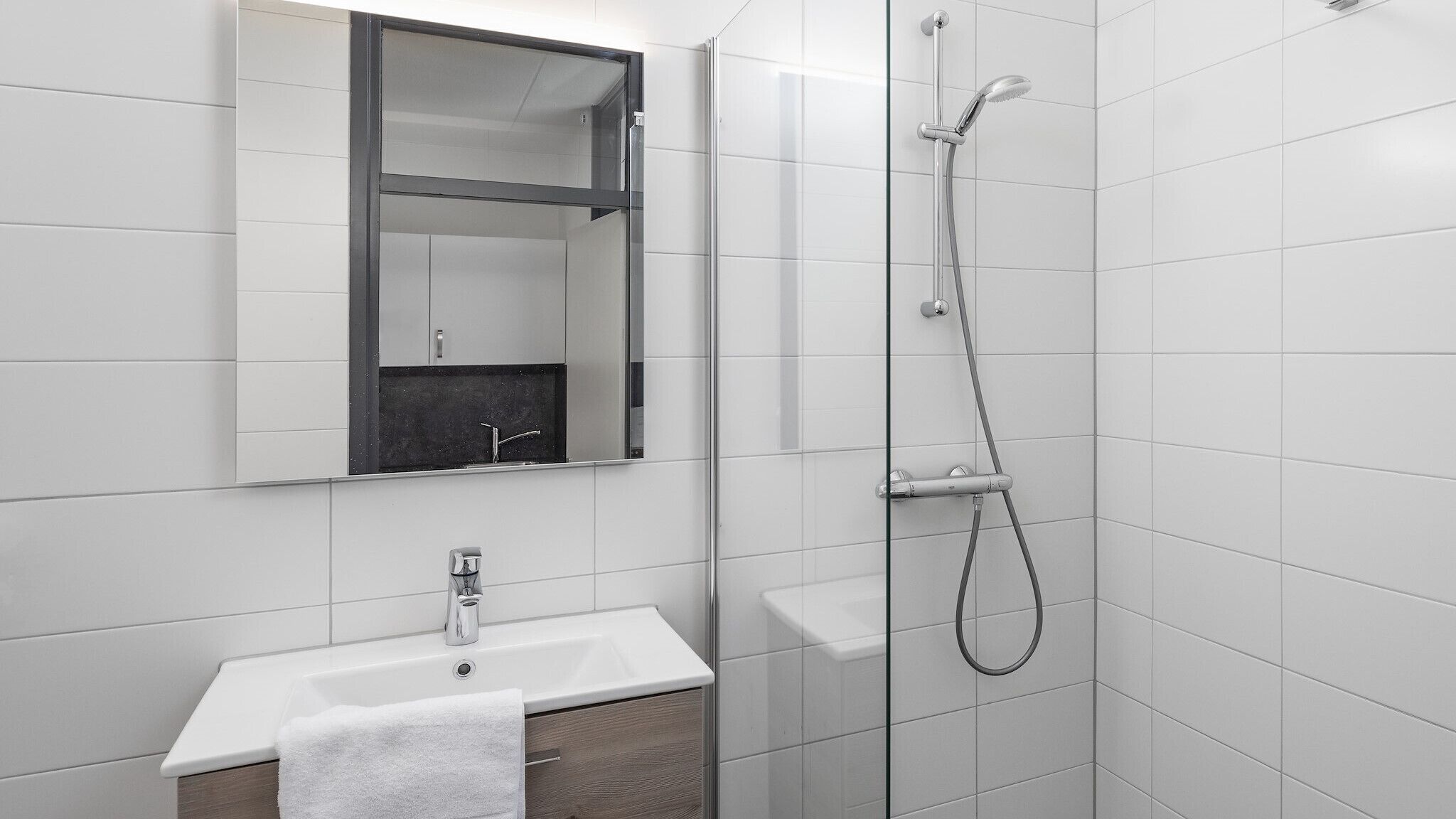Une salle de bain moderne avec un lavabo blanc, un miroir et une douche.
