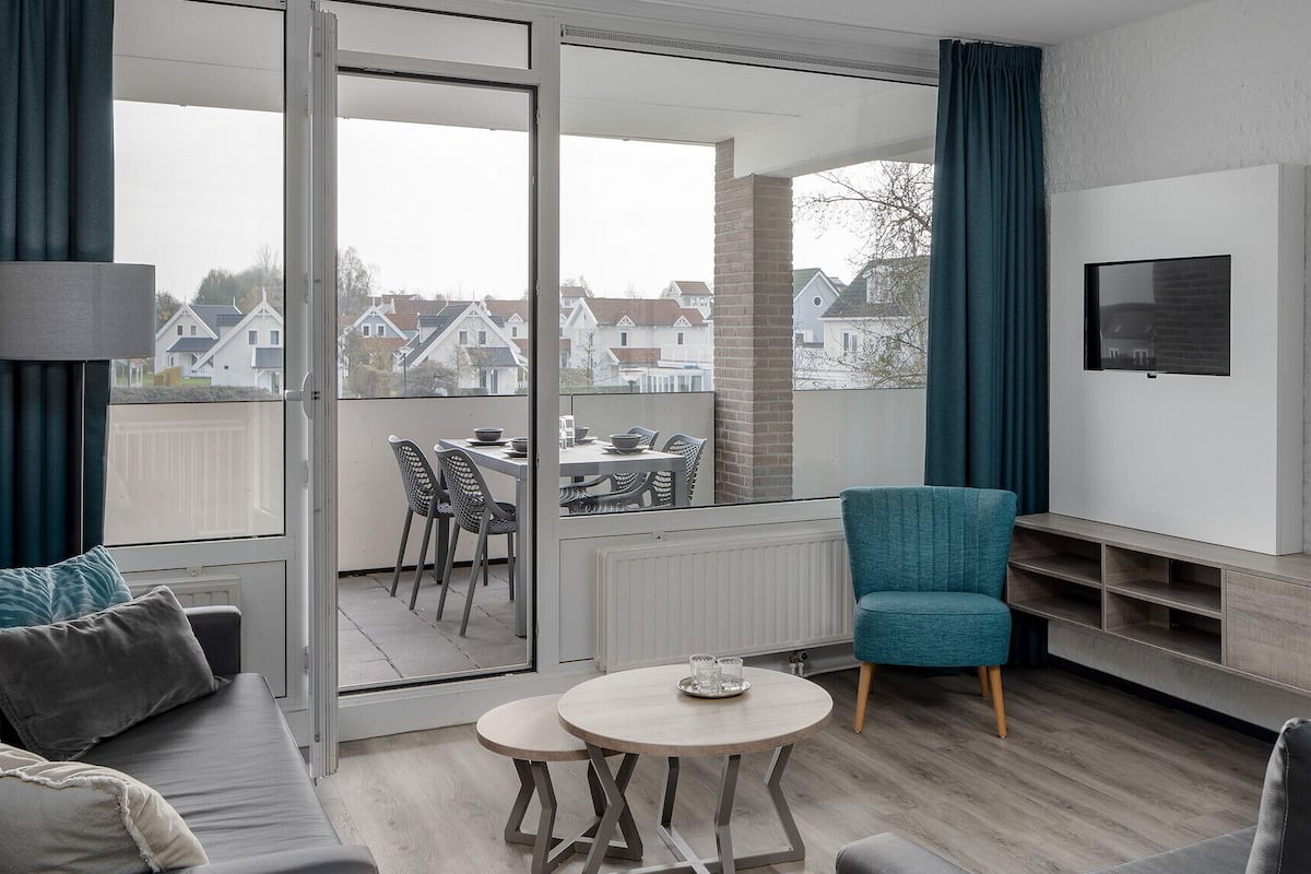 A modern living room with a balcony, a TV, and a dining area.