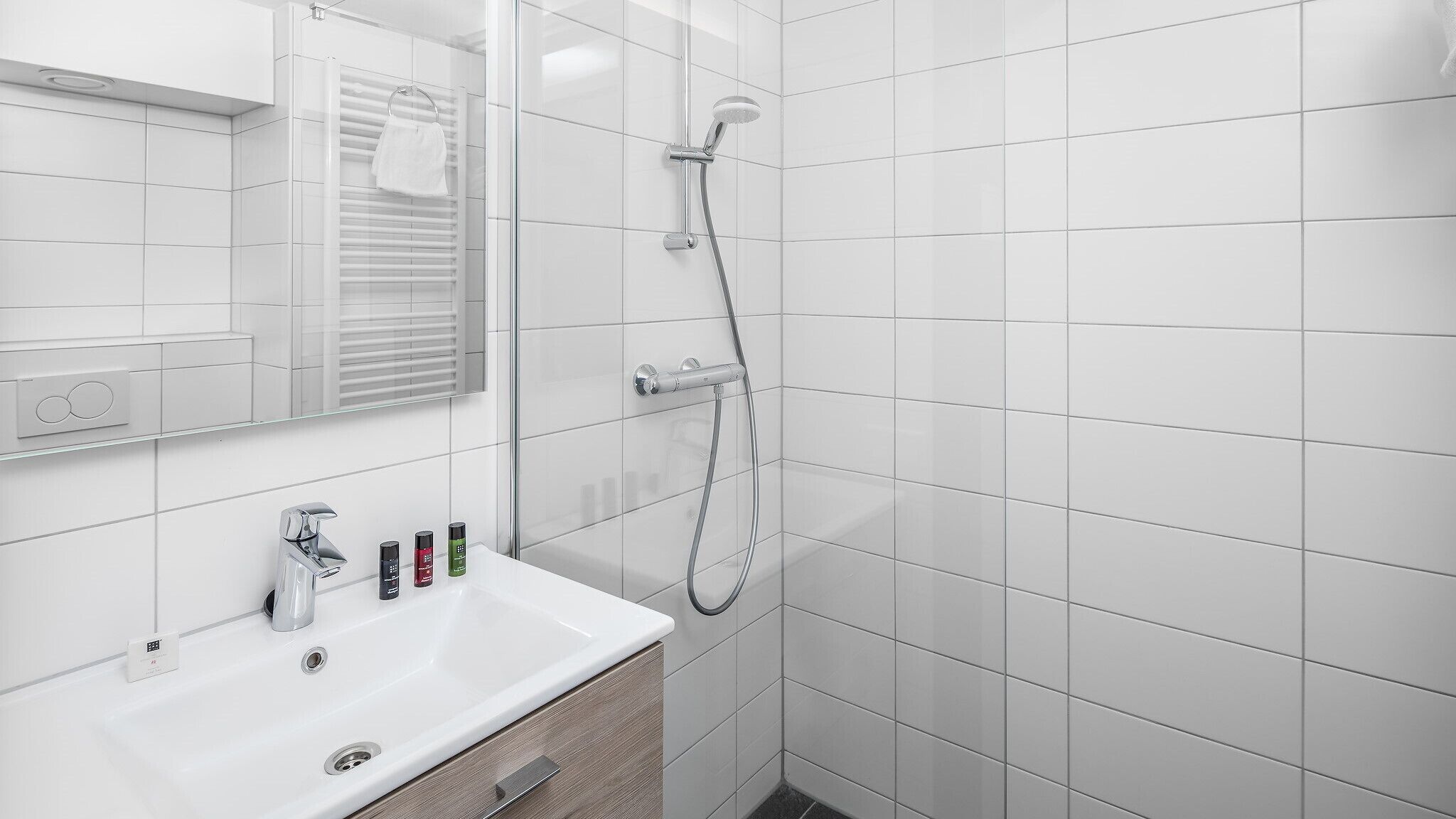 A modern bathroom with a white sink, mirror, and shower.