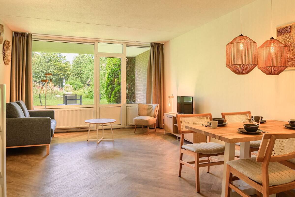 A cozy room with a dining table, chairs, a sofa, and a TV.