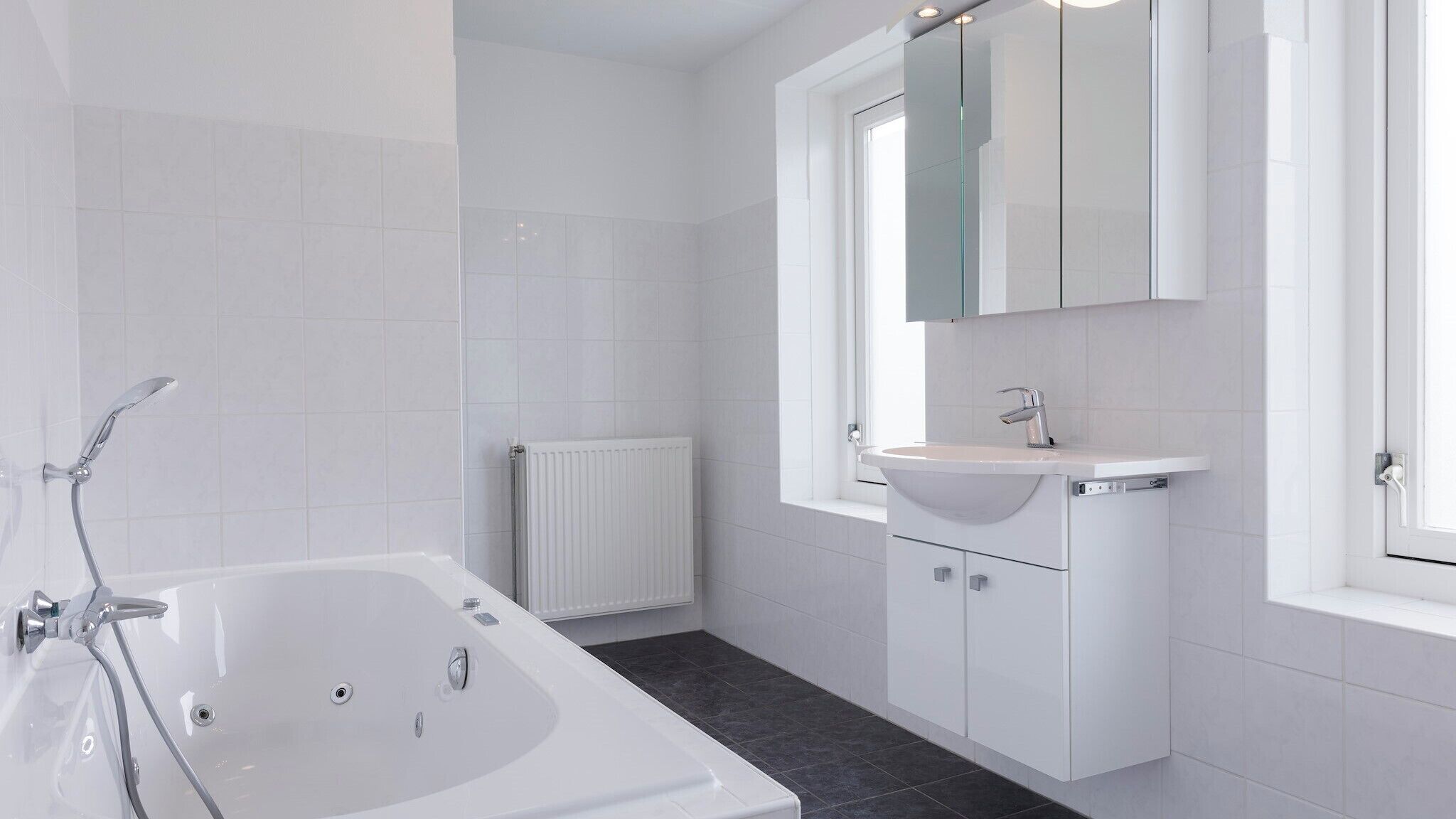 Un bagno moderno con una vasca, un lavandino e uno specchio.