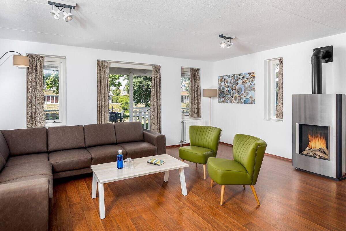 A modern living room with a brown sofa, a white coffee table, a green armchair, and a fireplace.