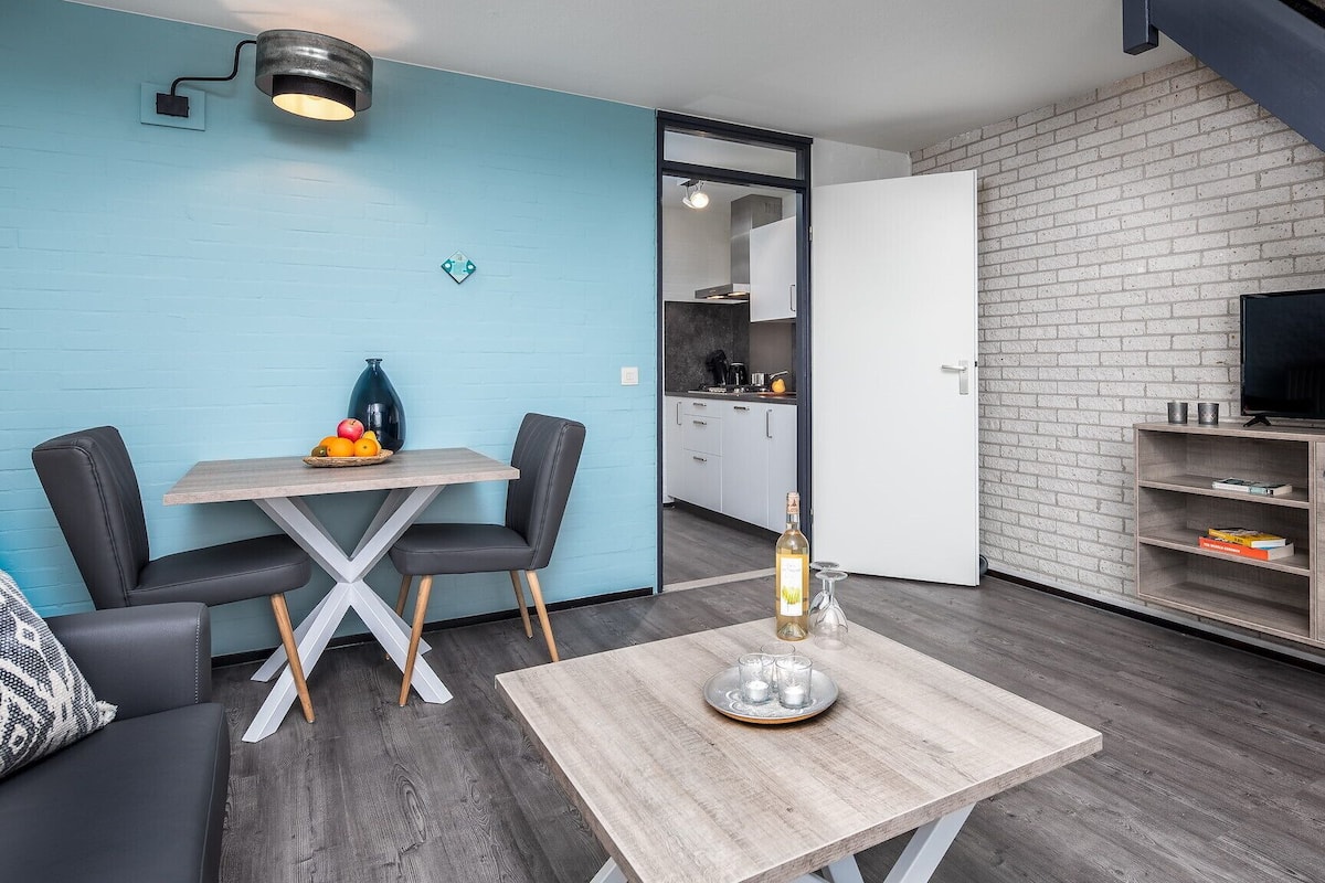 A compact living space with a dining area, kitchenette, and a TV.