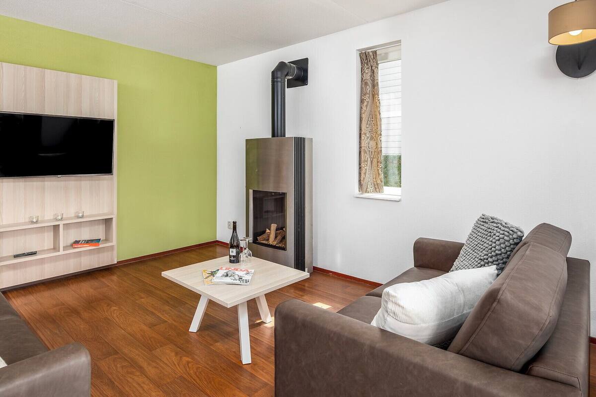 A modern living room with a flat-screen TV, a fireplace, and a dining area visible in the background.