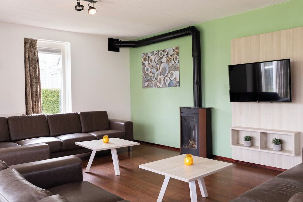 A living room with a sofa, two coffee tables, a fireplace, a TV, and a wall with a picture.