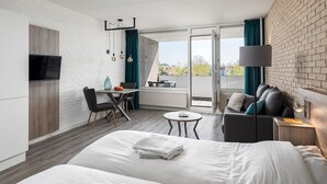 Una habitación de hotel moderna con cama, escritorio, sofá y balcón con vistas.