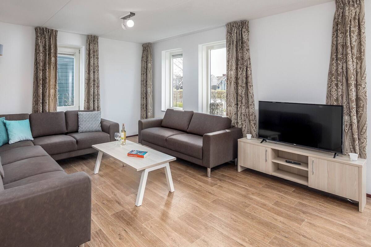A modern living room with two sofas, a coffee table, a TV, and patterned curtains.