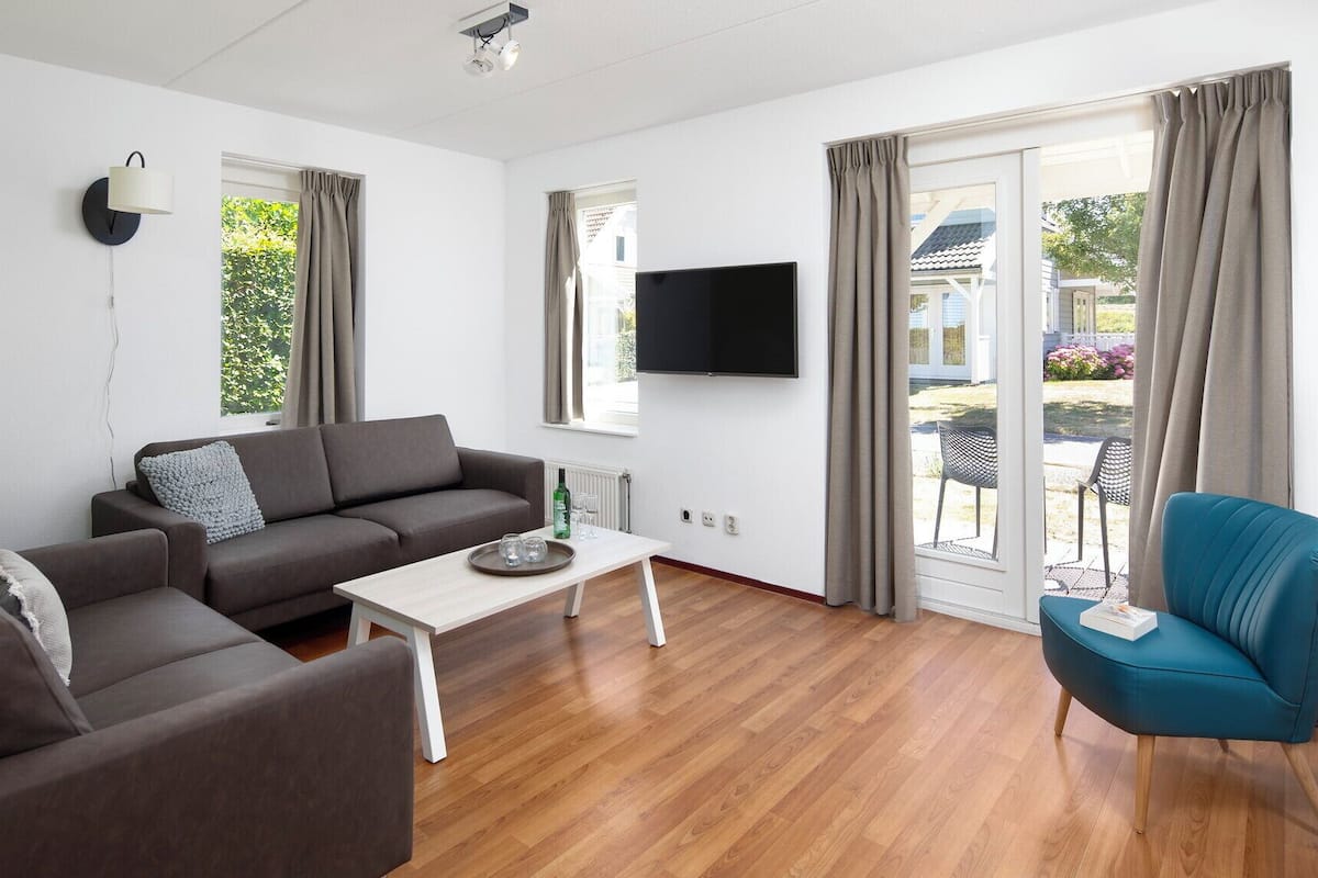 A modern living room with a grey sofa, a small white table, and a teal armchair.
