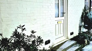 A white brick building with a door labeled '99', a small window, and a mailbox. - Seaside Bliss Apartment for Style and Comfort (Cleethorpes)