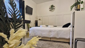 A modern hotel room with a large bed, a flat-screen TV, a small plant, and a decorative wall piece. - Seaside Bliss Apartment for Style and Comfort (Cleethorpes)