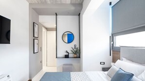 A modern bedroom with a bed, a bedside table, a mirror, and a wall-mounted TV.