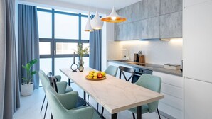 A modern kitchen with a marble countertop, a dining table with chairs, and pendant lights.