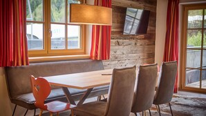 Un coin repas chaleureux avec une table en bois, quatre chaises et un banc.