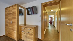 Une chambre d’hôtel meublée en bois, dotée d’un téléviseur à écran plat et d’un couloir menant à un espace repas.