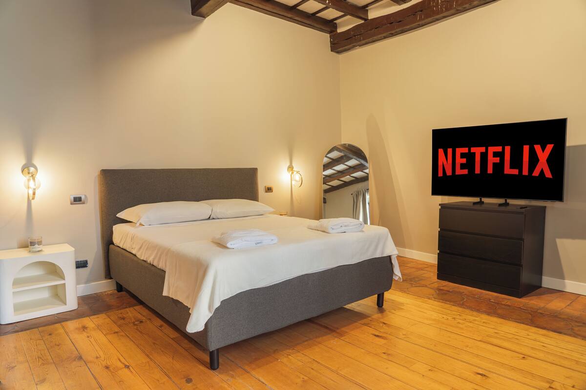 Une chambre à coucher avec un lit, des lampes de chevet, une télévision et un plancher en bois.