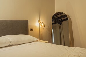 A hotel room with a bed, a nightstand, a wall-mounted lamp, and a large mirror. - CB Rooms Campo Dei Fiori (Rome)