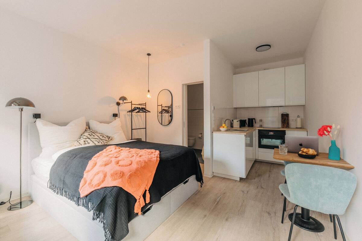 Una camera da letto con un letto, un comodino e un angolo cottura.