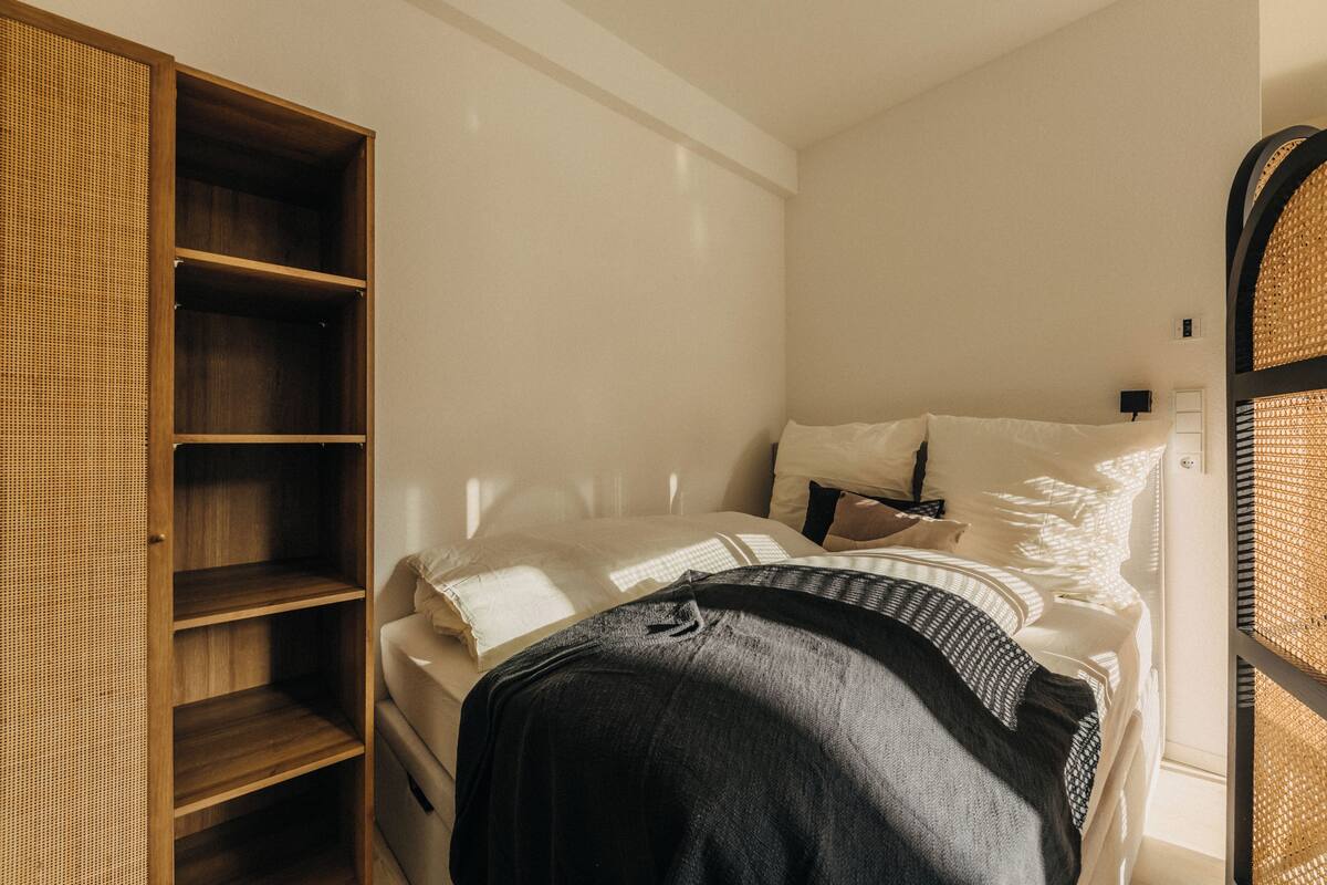 Una camera da letto con un letto, un armadio in legno e una sedia in vimini.