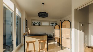 Una cocina moderna con encimera negra, dos taburetes de madera y una lámpara colgante.