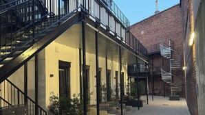 Un patio con una escalera que lleva a un balcón, rodeado de edificios con fachadas de ladrillo.