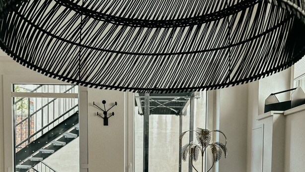 Una sala de estar moderna con un sofá, una mesa redonda y vistas a una escalera que da al exterior.
