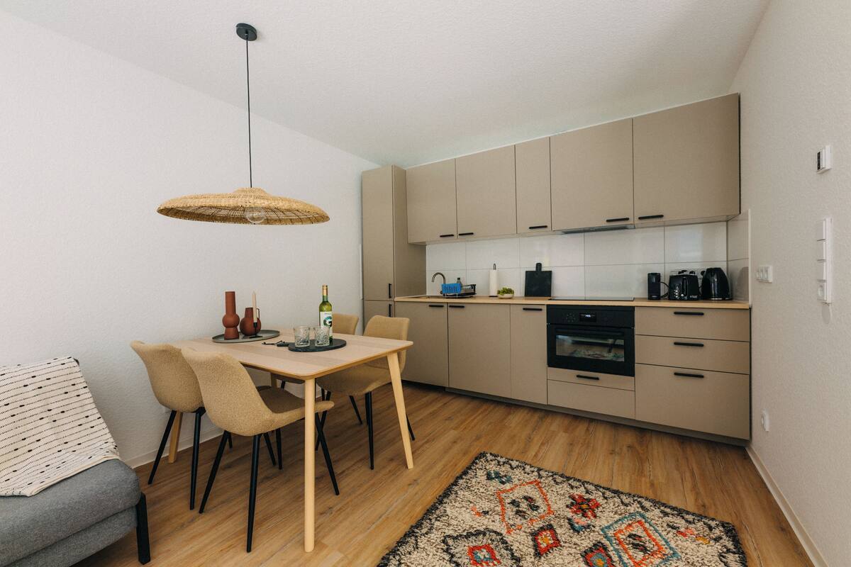Una cucina moderna con mobili in legno, un tavolo da pranzo con sedie e un lampadario.