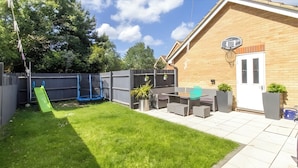 A backyard with a trampoline, a patio table, and a basketball hoop. - Pet Friendly - Parking - 3 Bedrooms - 6 Guests (Canterbury)