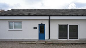 A building with a blue door, a window, and a sliding glass door. - Heathercroft Apartment-Modern Comfort in Fort William. (Fort William)