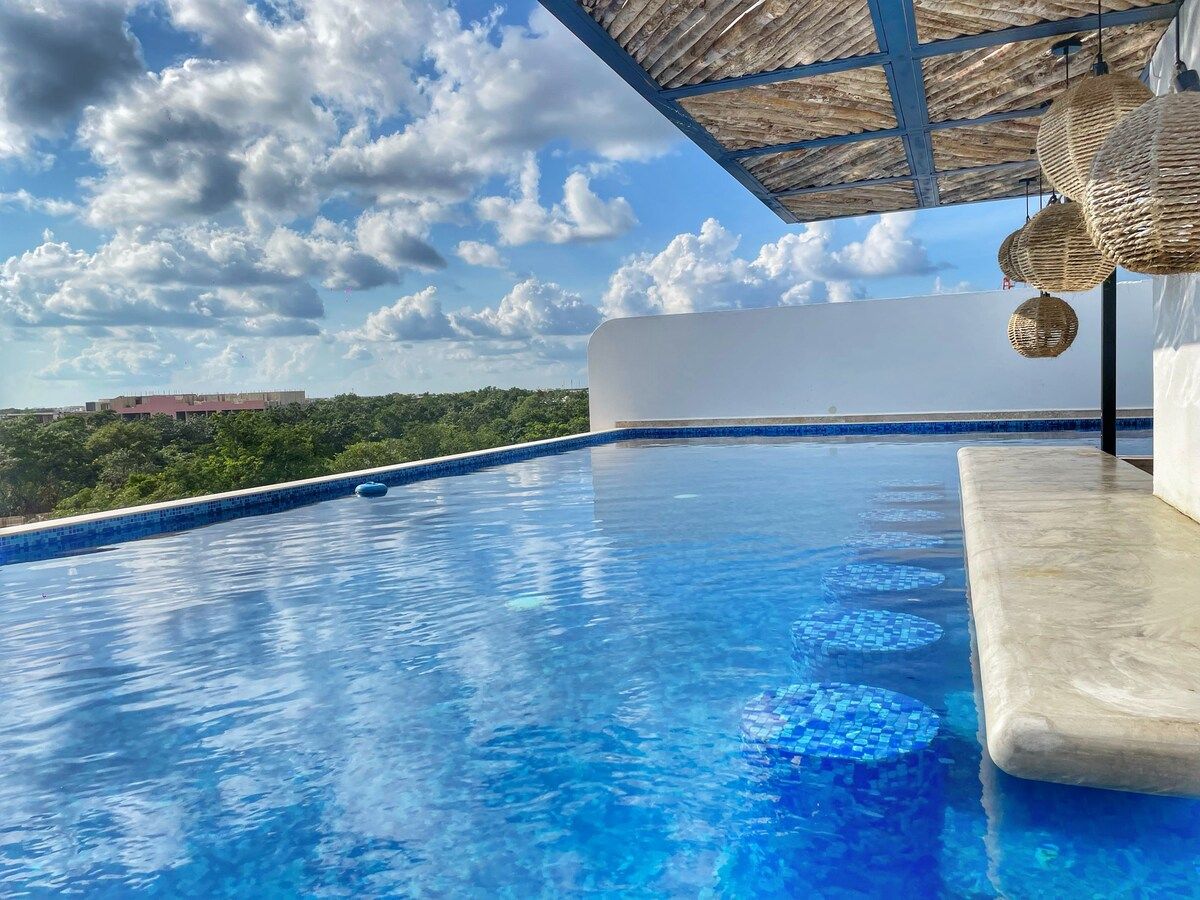 Una piscina a sfioro con acqua cristallina, una parete bianca e vista sul paesaggio.