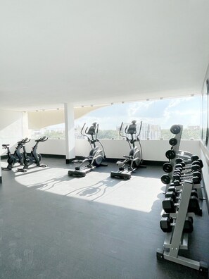 A gym with exercise equipment including stationary bikes, treadmills, and dumbbells.