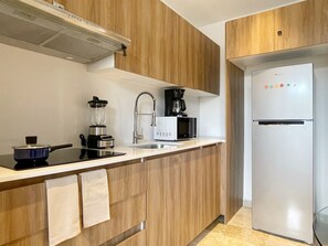 Une cuisine moderne avec des meubles en bois, un réfrigérateur en acier inoxydable, une machine à café et un four à micro-ondes.