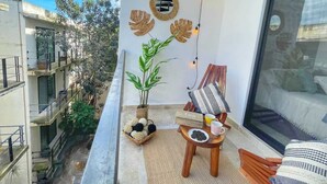 Un balcon agrémenté d’un pot de fleurs, une petite table avec une théière, des tasses et un panier de biscuits.