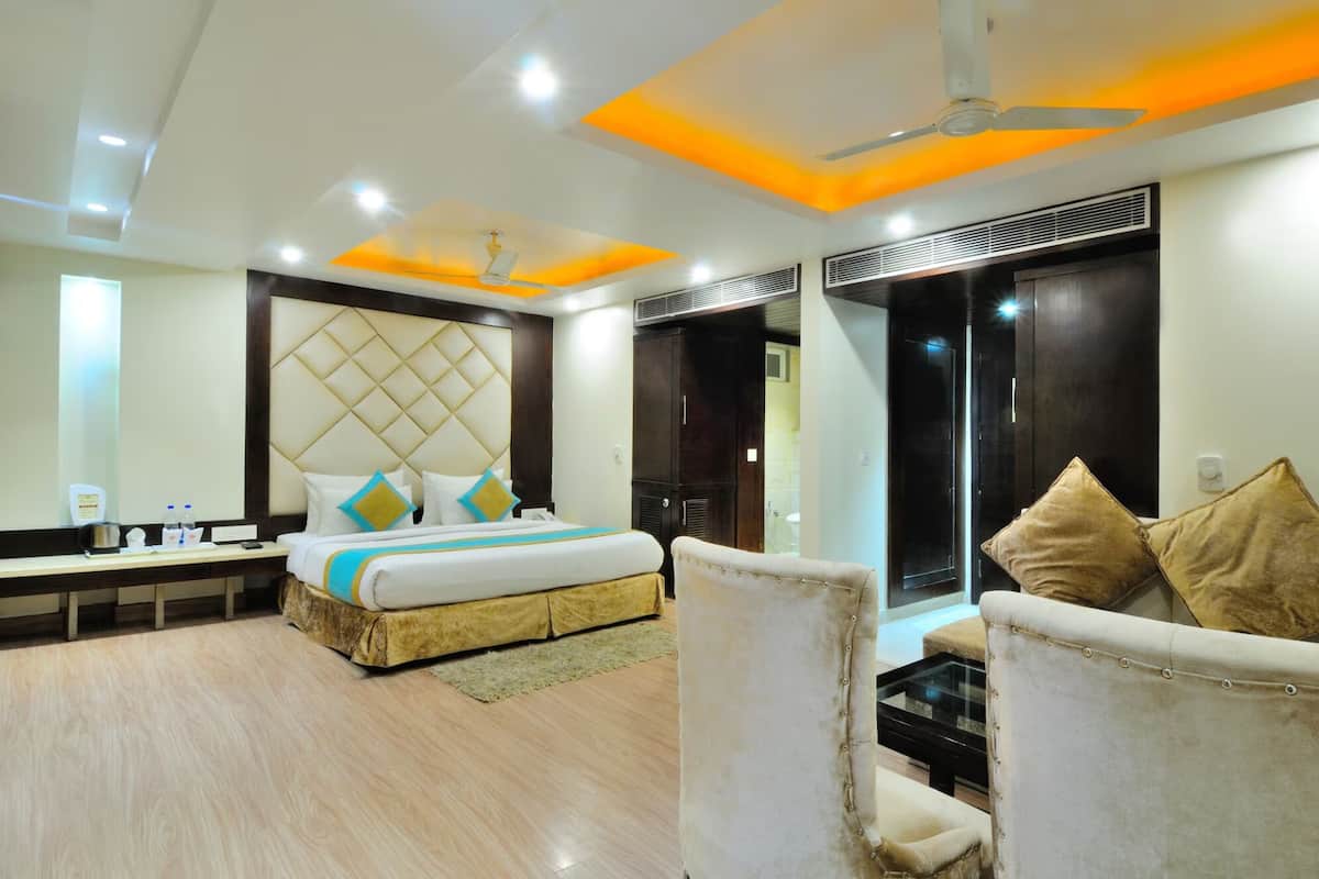 A modern hotel room with a large bed, a sofa, a desk, and a mirror.