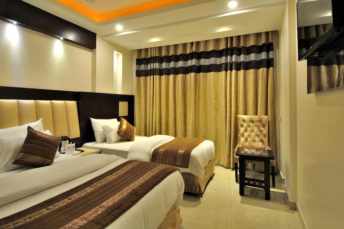 A hotel room with two beds, a chair, a ceiling fan, and a large window with curtains.