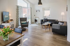 Un salon moderne avec un canapé, une table à manger décorée de tulipes, un téléviseur et une cheminée.