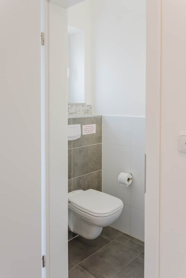 A small, clean bathroom with a toilet, a towel dispenser, and a toilet paper holder.