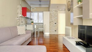 A modern living room with a sofa, TV, and a dining area with a table and chairs.