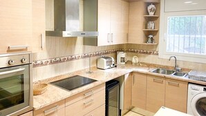 Eine moderne Küche mit Holzausstattung, einer Edelstahl-Dunstabzugshaube, einem Geschirrspüler und einem eingebauten Backofen.