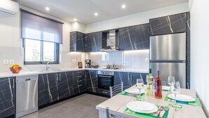 Een moderne keuken met donkere marmeren kastjes, roestvrijstalen apparatuur en een eethoek voor twee personen.