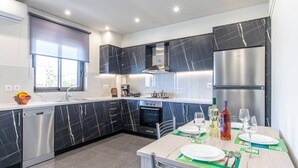 Una cucina moderna con pensili in marmo scuro, elettrodomestici in acciaio inossidabile e un'area pranzo per due persone.