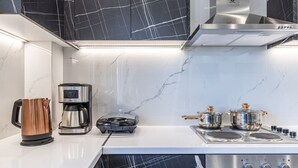 Una cucina moderna con una macchina da caffè, un bollitore e due pentole sul fornello.