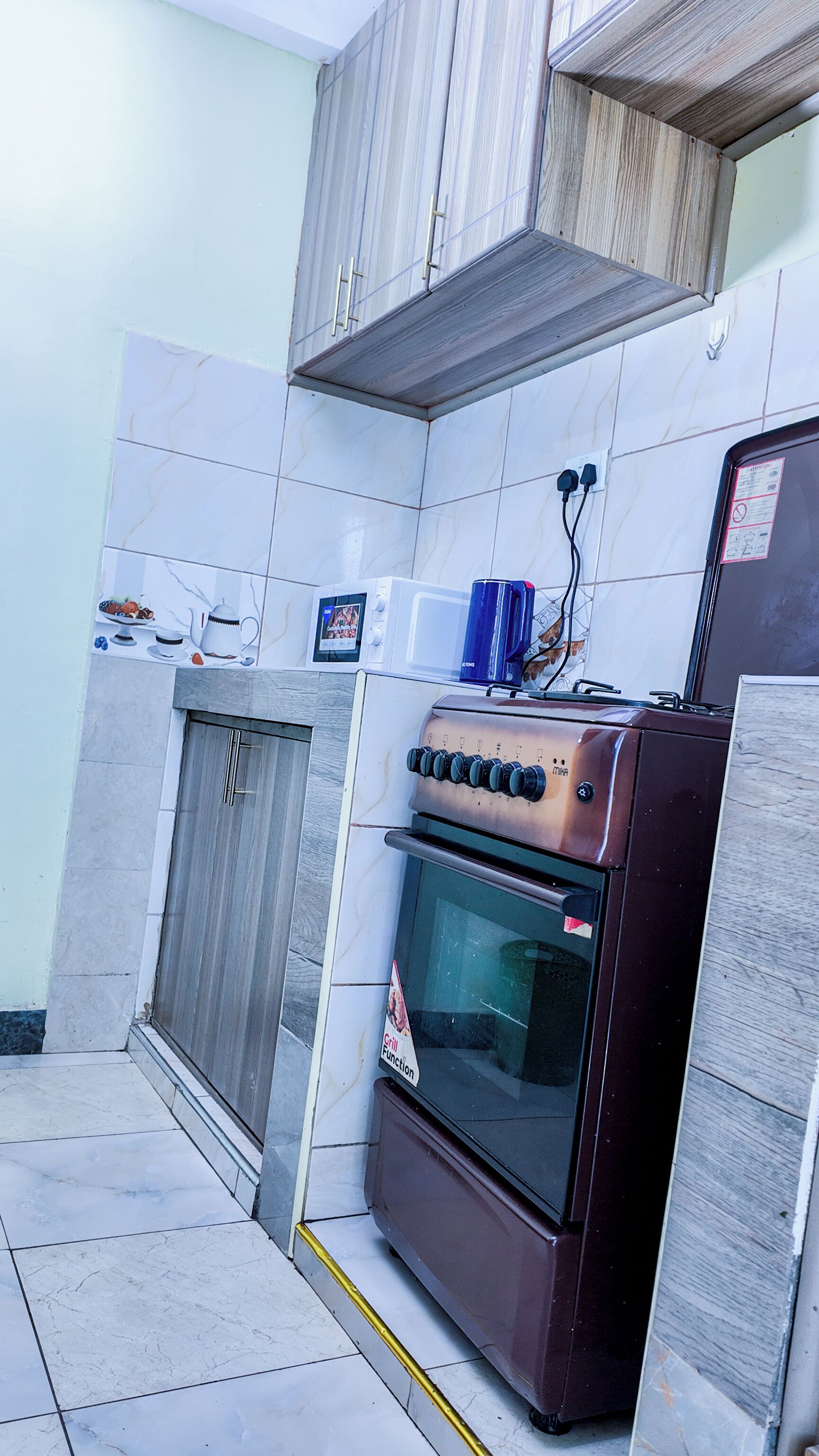 A compact kitchen with a built-in oven, a microwave, and a small cabinet.