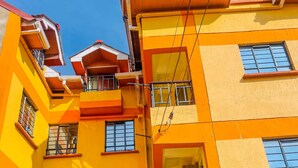 A multi-story building with balconies and windows, featuring a yellow and orange color scheme. - Zedek Suites (Nairobi)