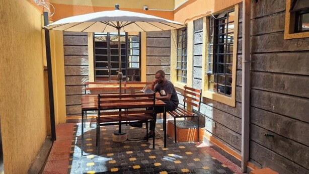 A wooden bench and table in a covered outdoor area with a tiled floor. - Zedek Suites (Nairobi)