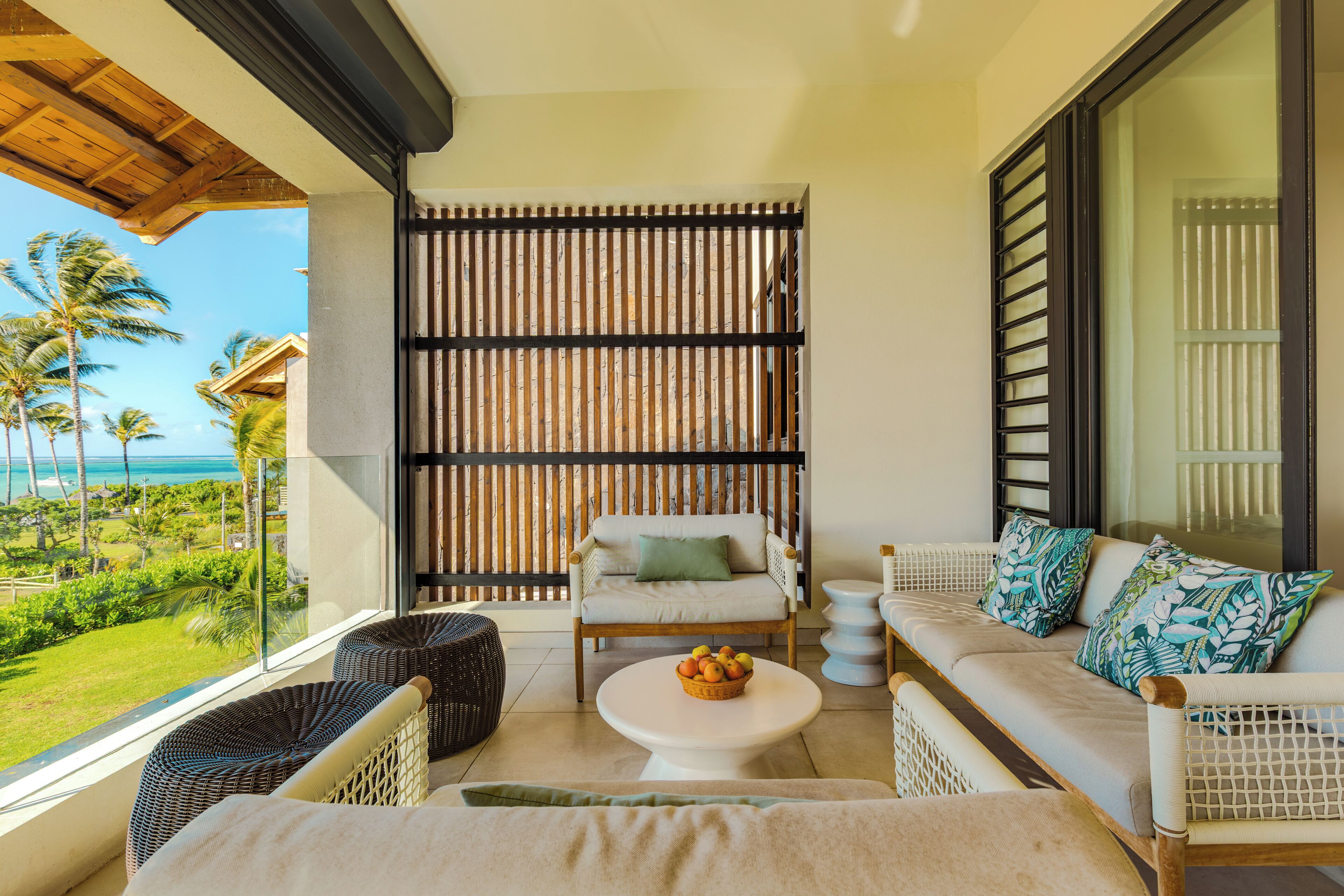 A balcony with wicker furniture, a white table, and a view of the ocean.