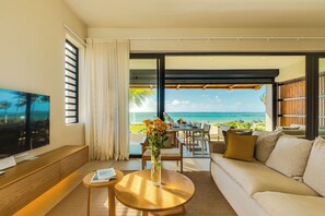 Ein modernes Wohnzimmer mit großem Fernseher, einem runden Holztisch, einer Couch und Meerblick.