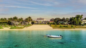 Un resort con varias edificaciones, una playa y un barco en el agua.