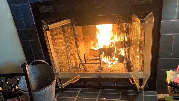A fireplace with a fire, a metal bucket, and a striped rug. - Charming pet friendly renovated barn with backyard, in Stevensville (Stevensville)