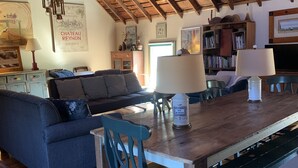A cozy living room with a wooden ceiling, a dining table, a sofa, and a chair. - Charming pet friendly renovated barn with backyard, in Stevensville (Stevensville)